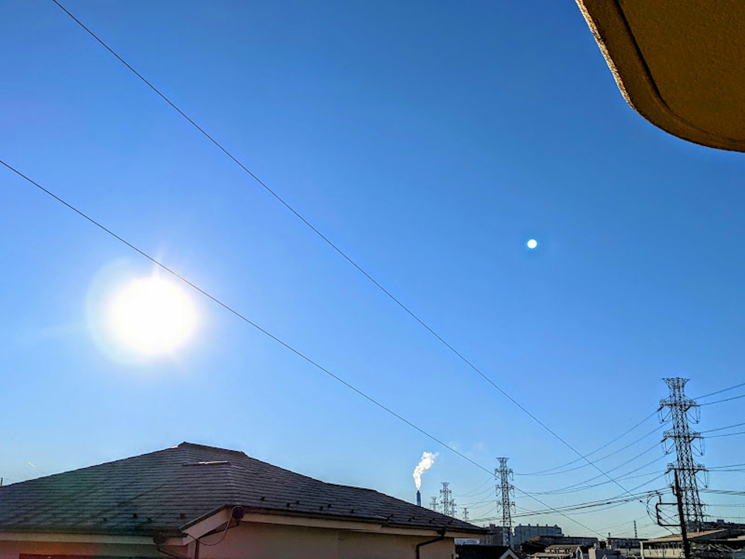 Cielo azul claro con el sol y una chimenea visibles
