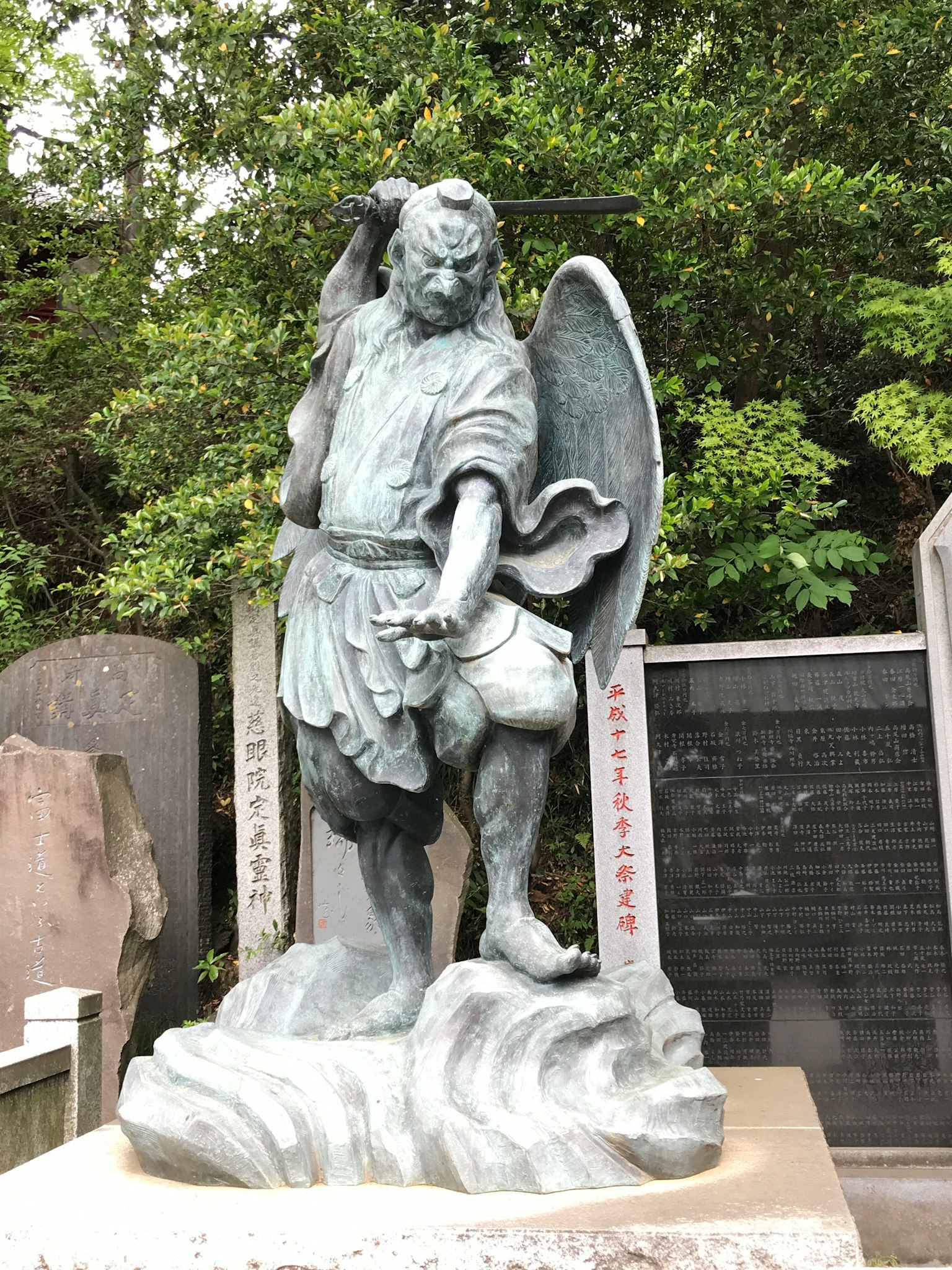 青铜天使雕像，手持剑和盾，站在岩石基座上