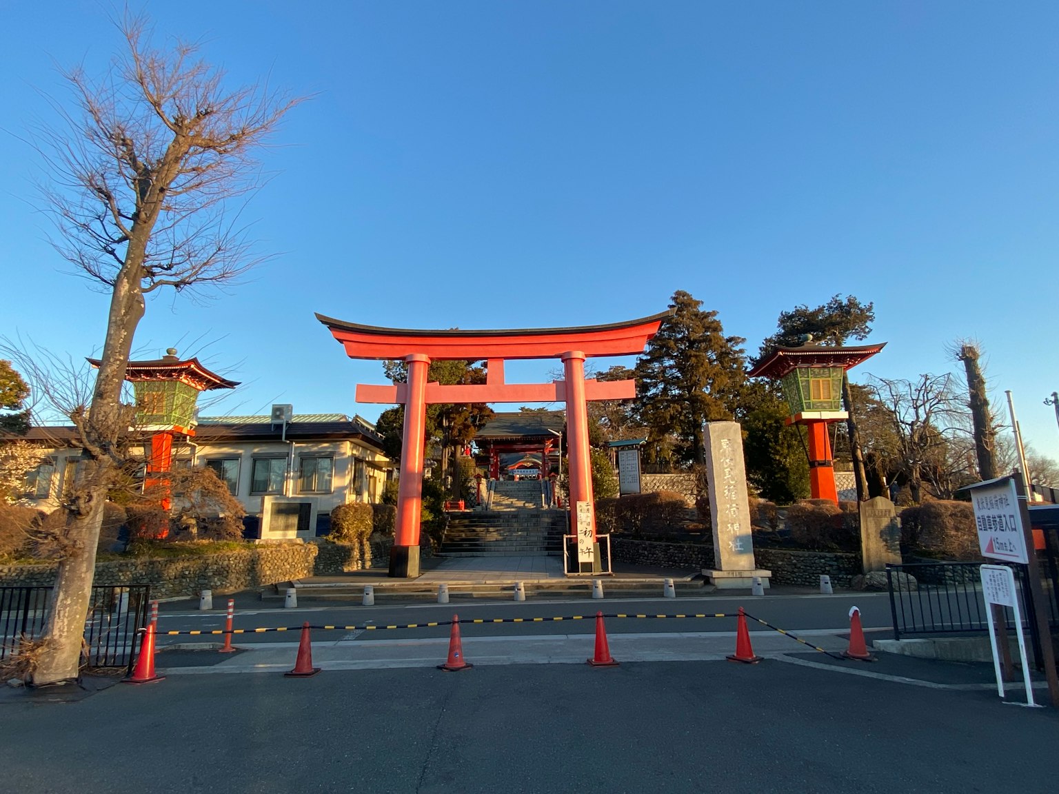 Vorderansicht eines Schreins mit einem roten Torii und umgebenden Bäumen