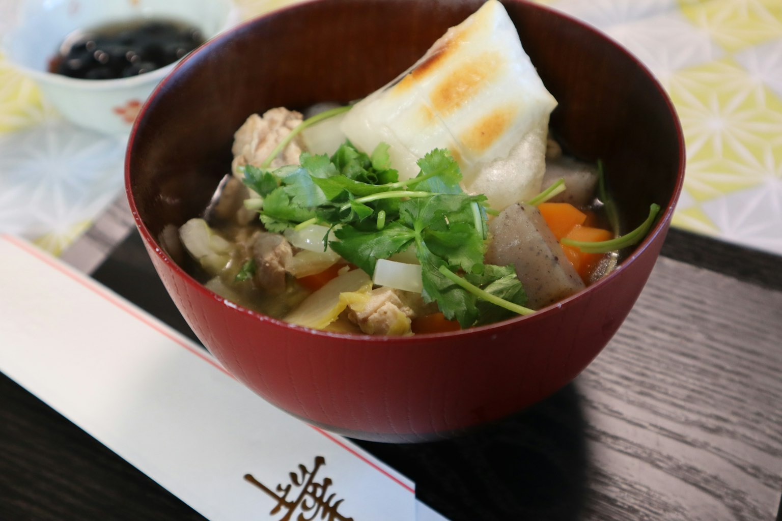 A bowl of hearty soup with various ingredients and herbs