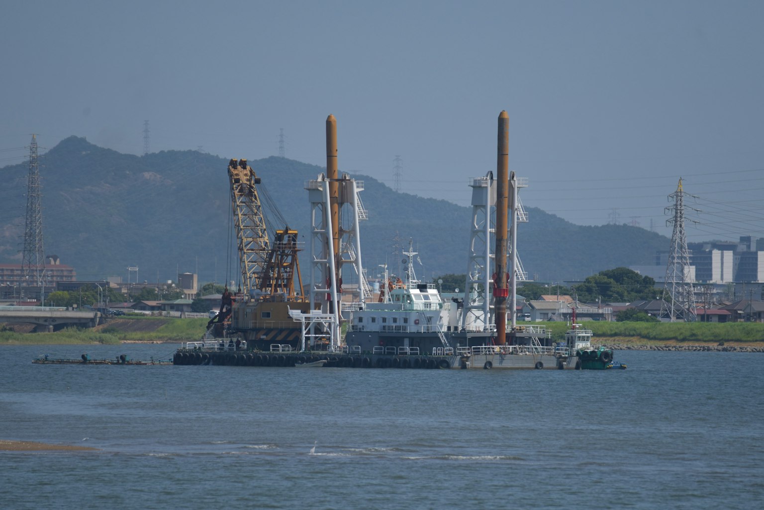 Barge xây dựng trên nước với núi ở phía sau