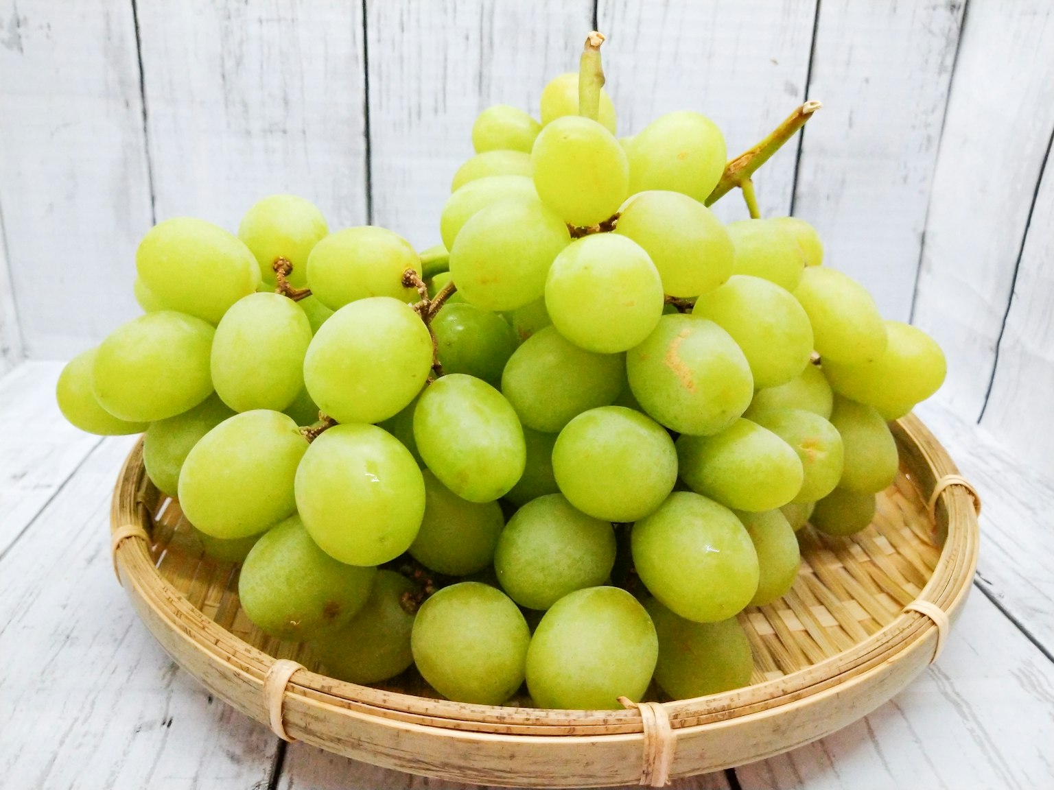 Une grappe de raisins verts dans un panier tressé