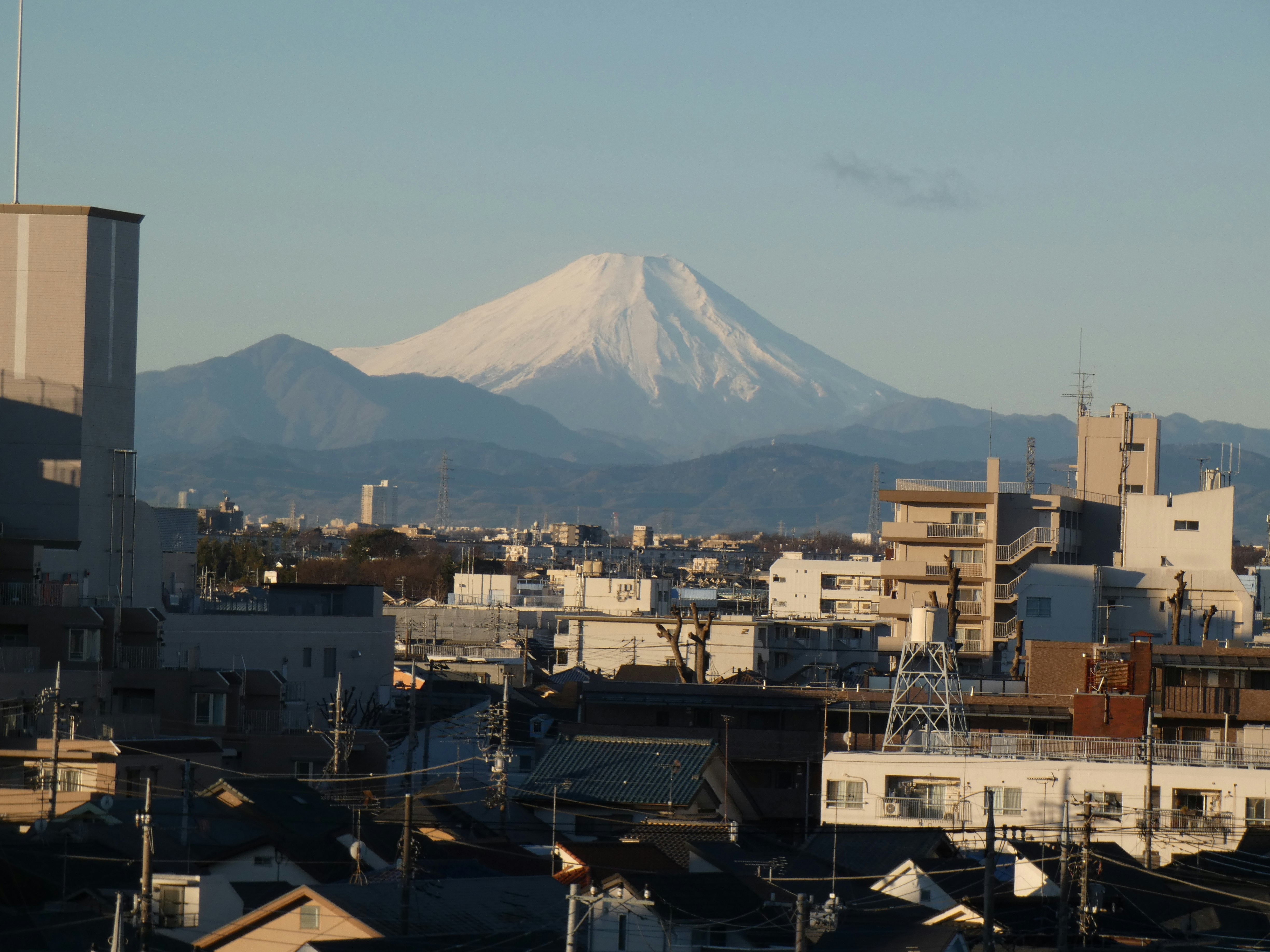 街並みの上にそびえる雪をかぶった山と夕暮れの空
