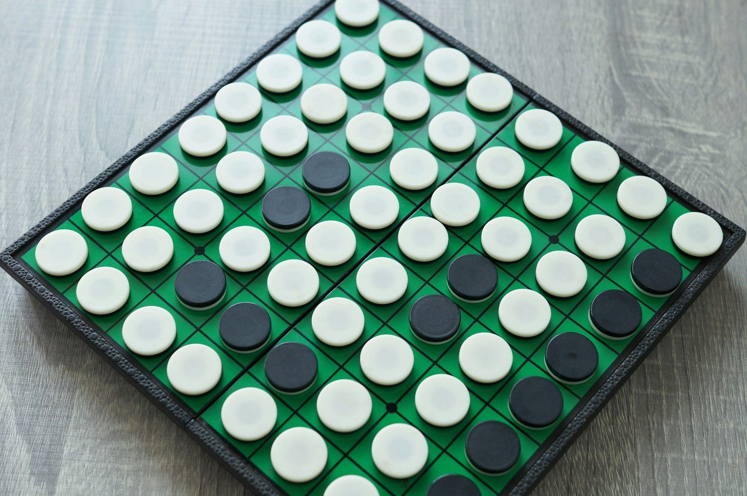 กระดานเกม Othello ที่มีพื้นสีเขียวและชิ้นส่วนกลมสีดำและสีขาว