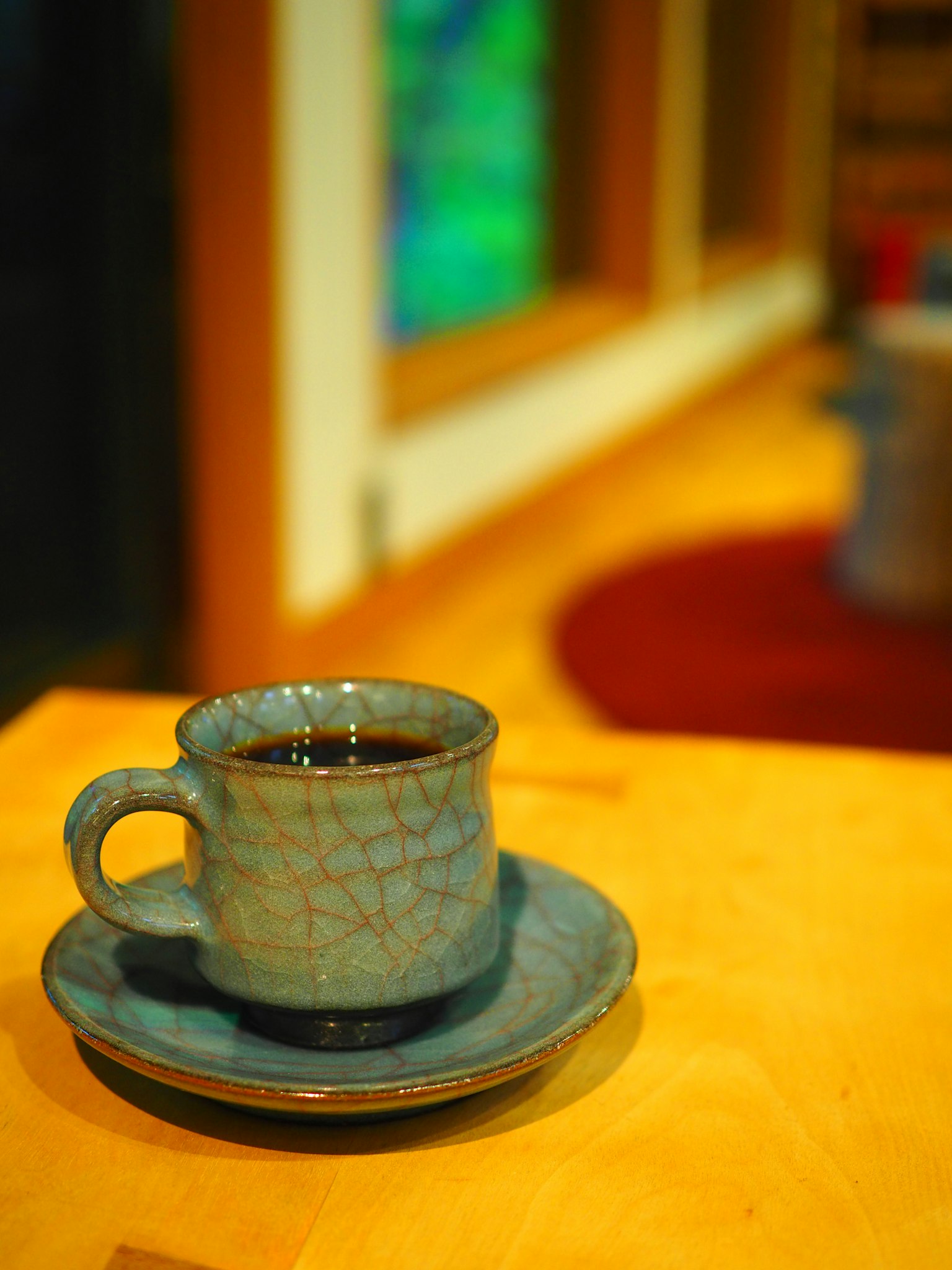 Sebuah cangkir keramik biru dengan kopi di atas meja kayu