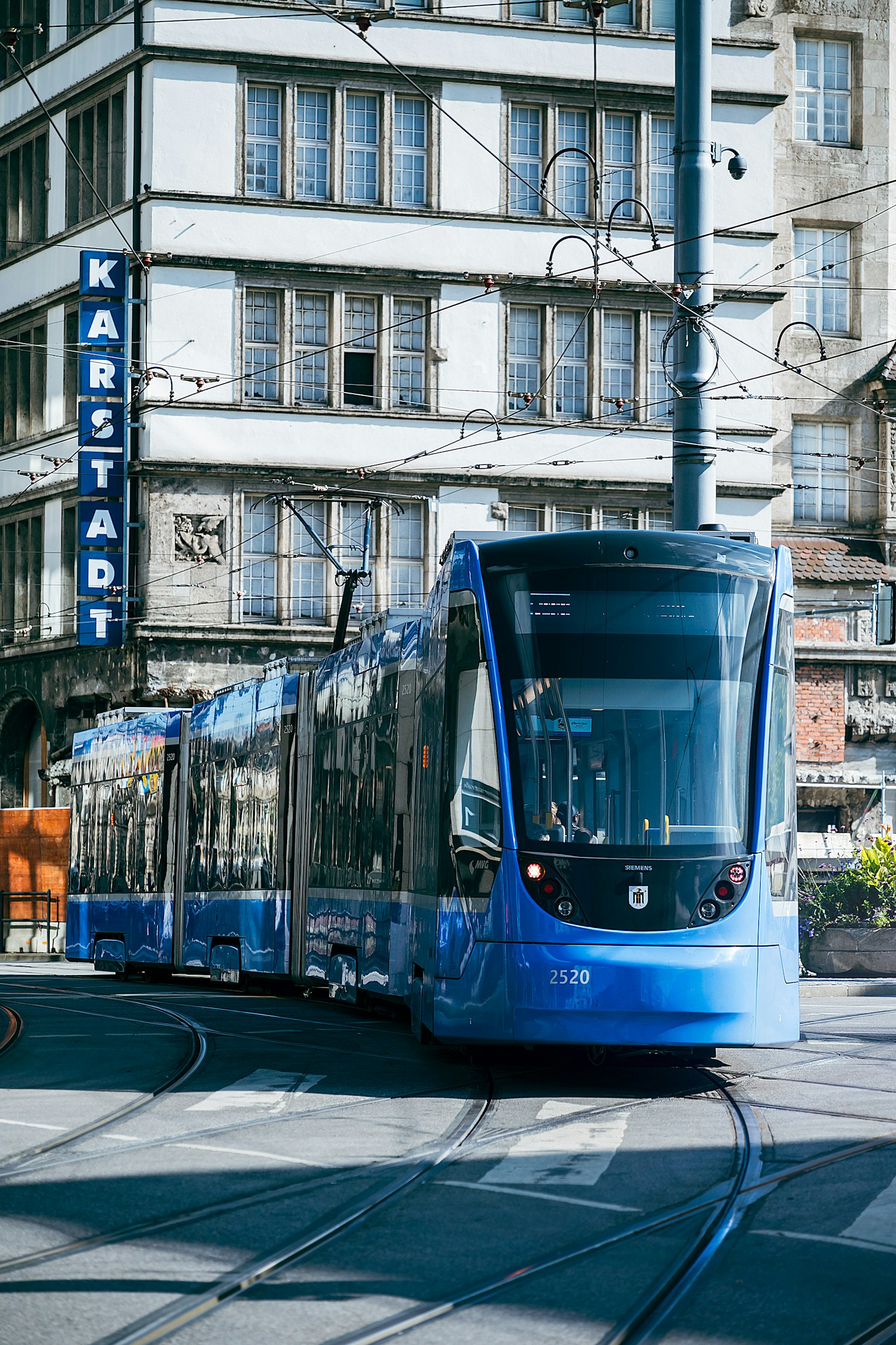 A blue tram passing in front of the Karstadt sign