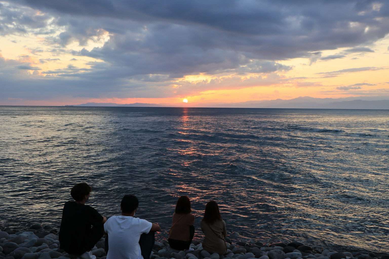 Menschen, die den Sonnenuntergang über einem ruhigen Meer beobachten