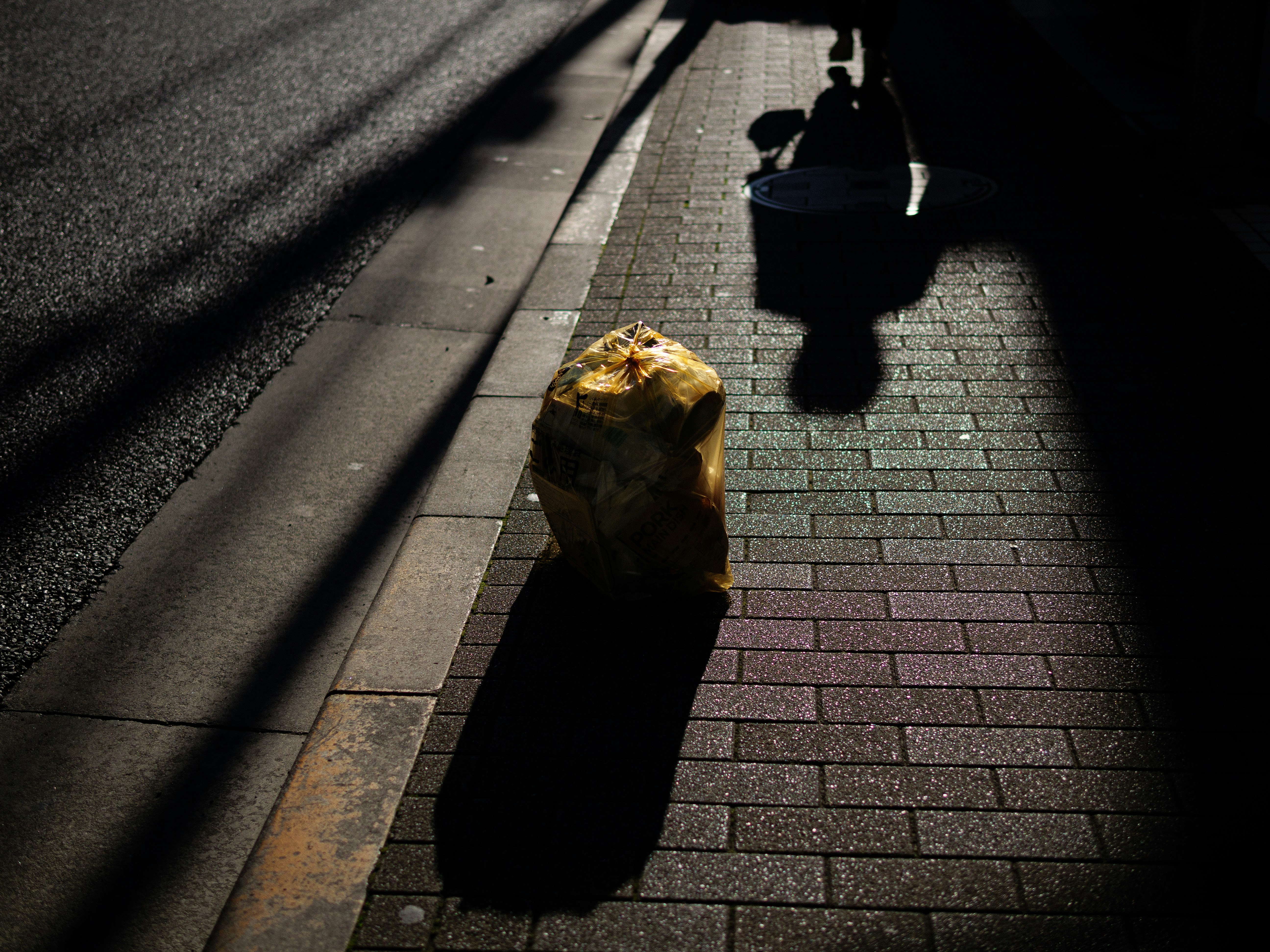 bolsa de plástico amarilla en una acera con sombras marcadas