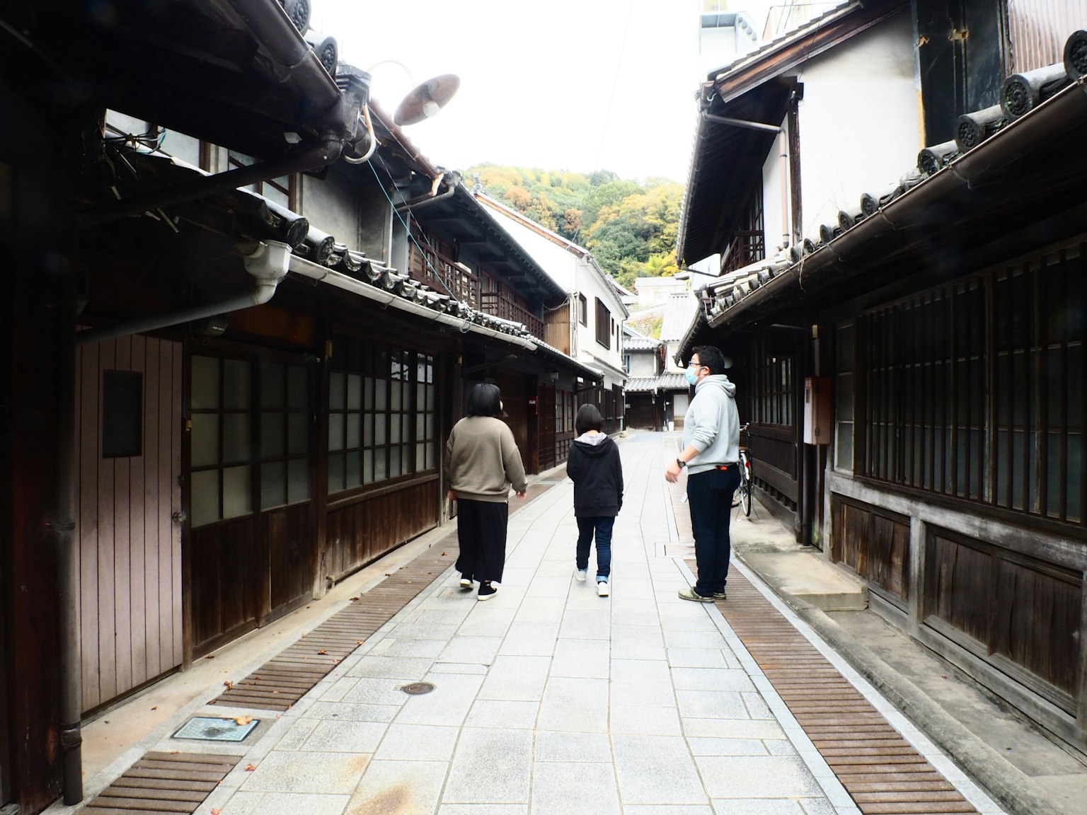 People walking down a narrow street lined with traditional buildings