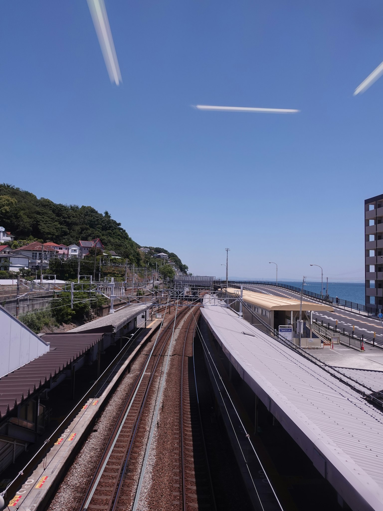 Eisenbahnschienen, die sich unter einem klaren blauen Himmel zum Meer winden