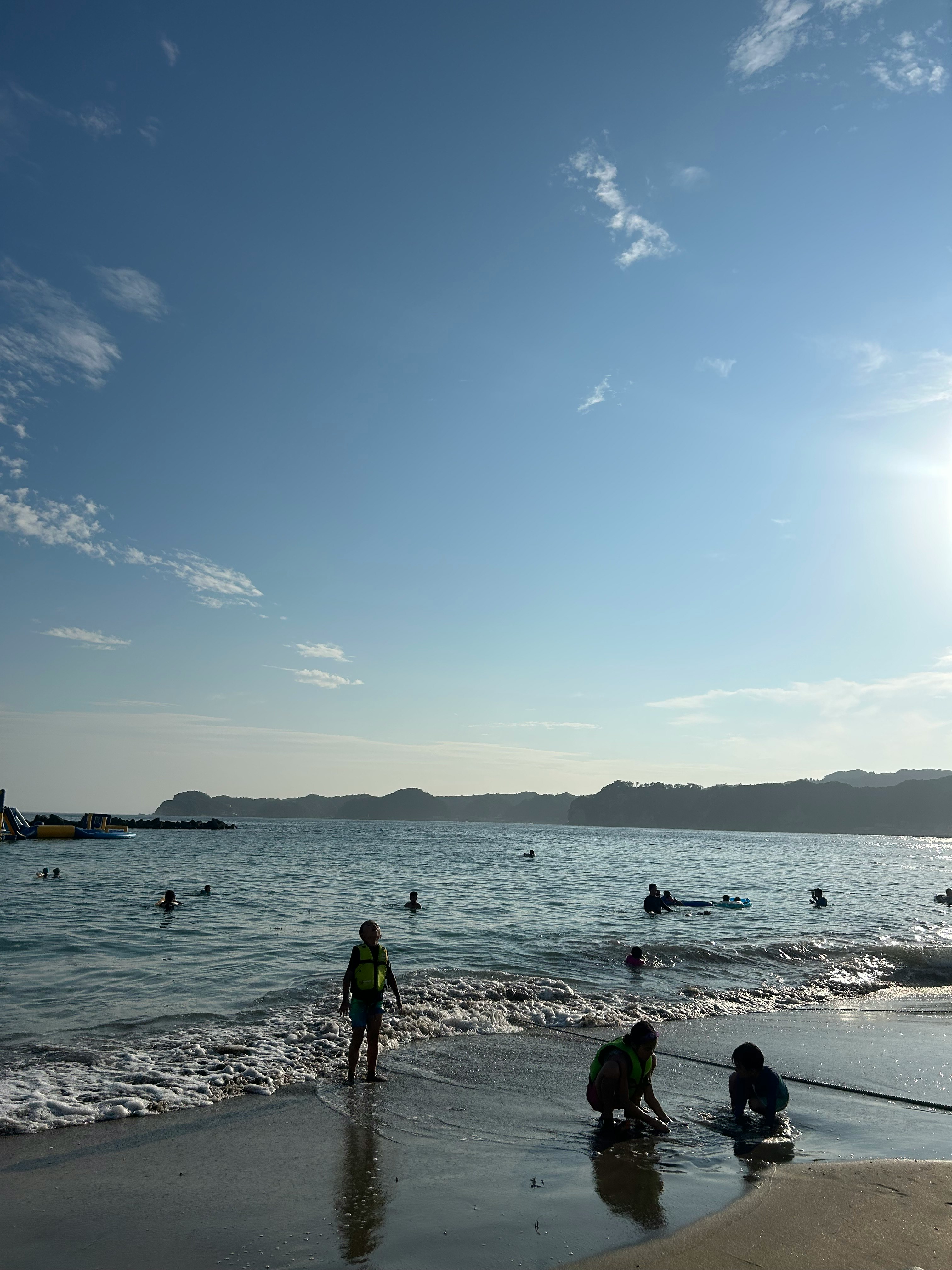 海辺の砂浜で遊ぶ人々と水平線のある海の風景