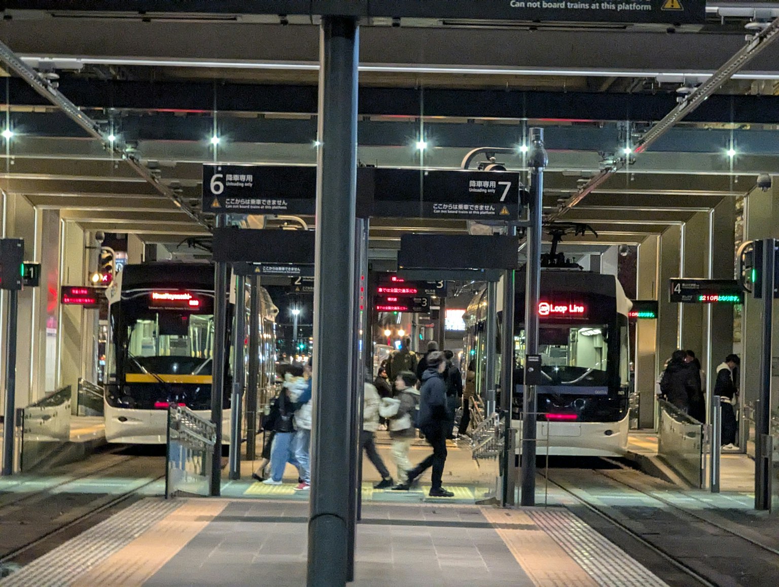 ภาพที่สถานีรถบัสในตอนกลางคืน มีผู้โดยสารข้ามไปข้ามมาและมีรถบัสจอดสองคัน