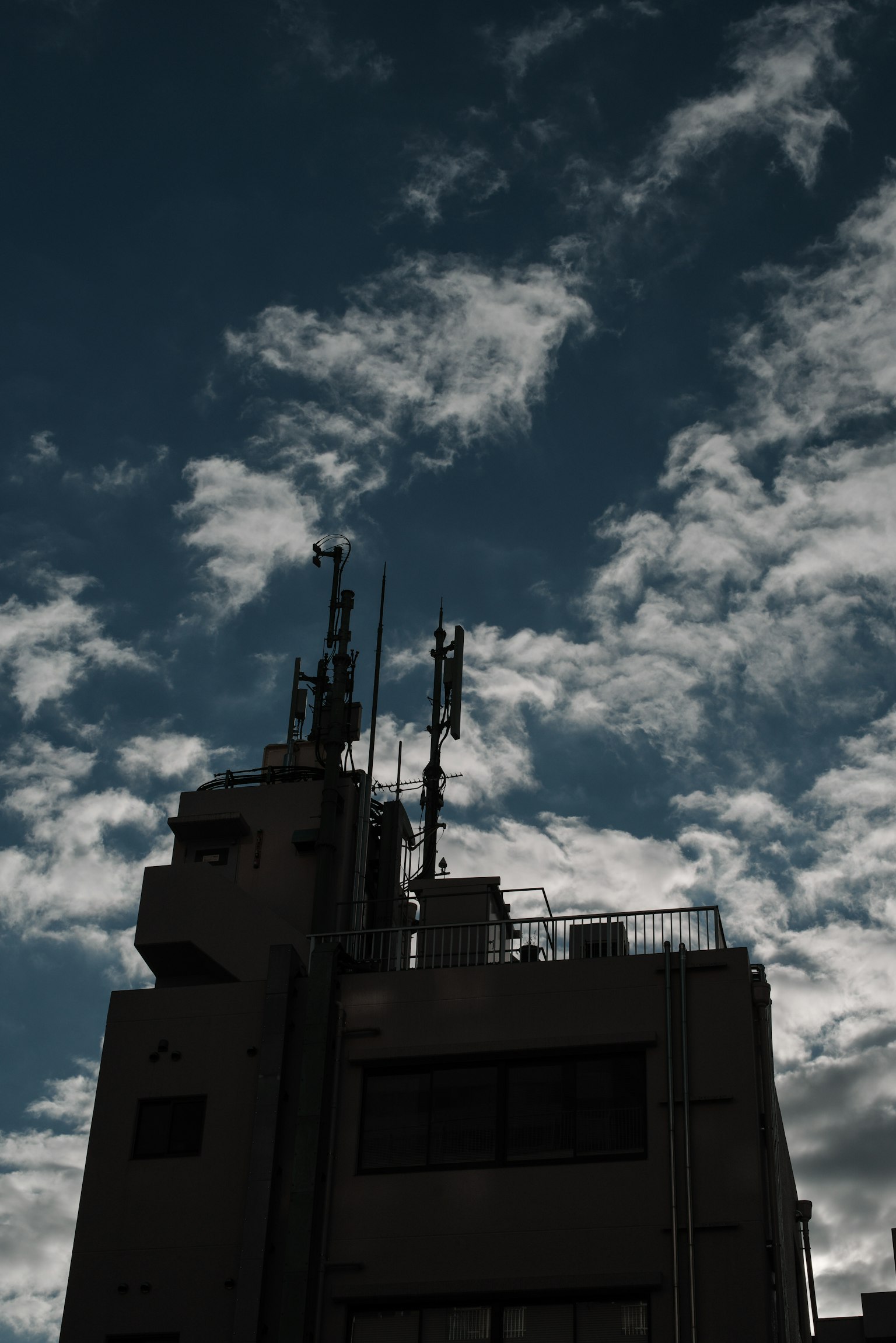 Silhouette gedung tinggi melawan langit biru dengan awan