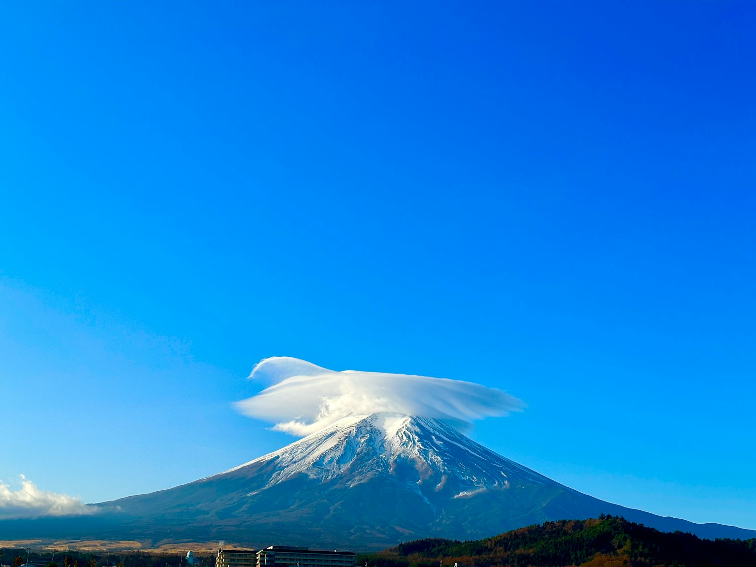 Schneebedeckter Fuji mit einer einzigartigen Wolkenformation unter klarem blauen Himmel