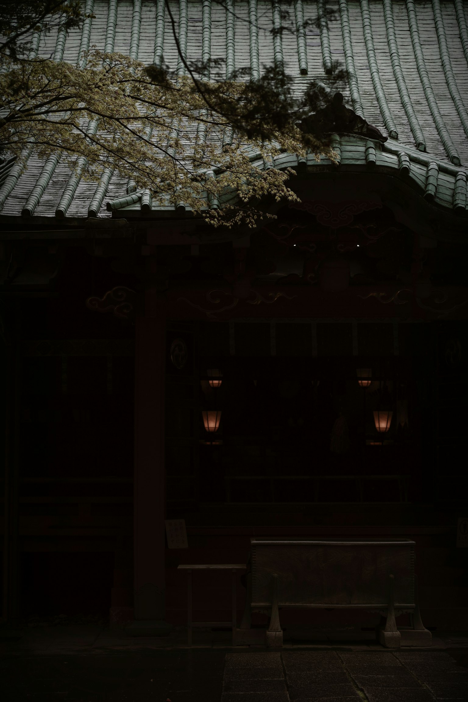 Entrée faiblement éclairée d'un sanctuaire avec un banc et des lanternes