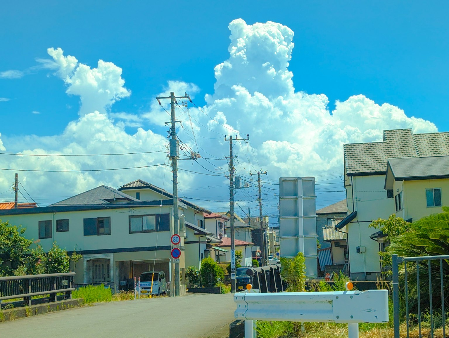 Rural landscape with blue sky and white clouds houses and utility poles lining a quiet road