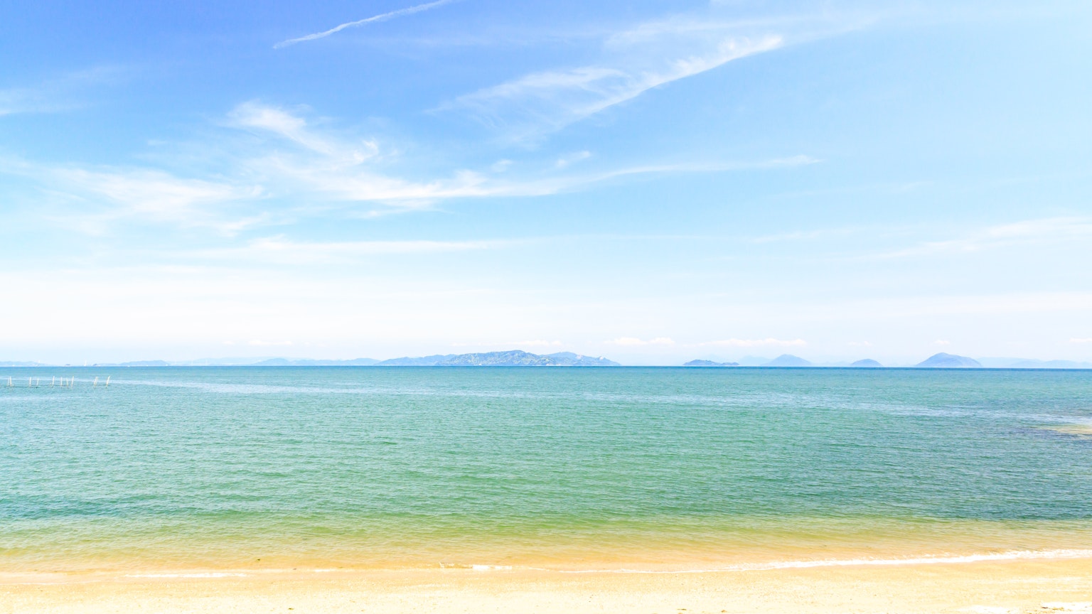 Eine ruhige Strandlandschaft mit blauem Himmel und ruhiger See