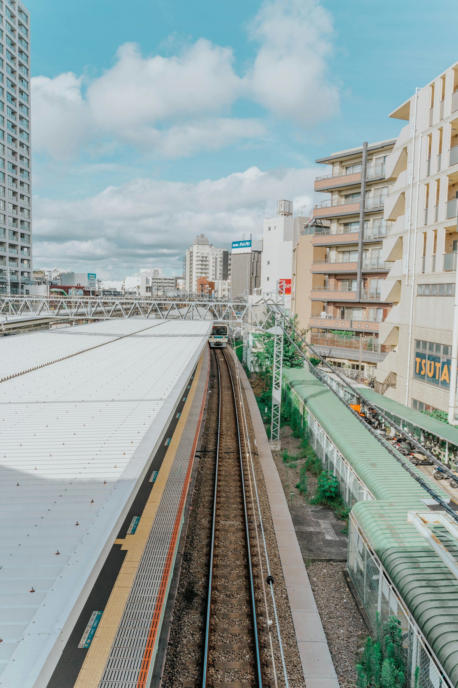 Vue d'une plateforme de gare et de voies ferrées avec des immeubles et des appartements en arrière-plan