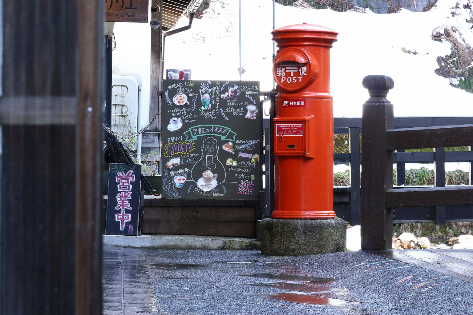 Cassetta postale rossa accanto a una lavagna in una zona panoramica