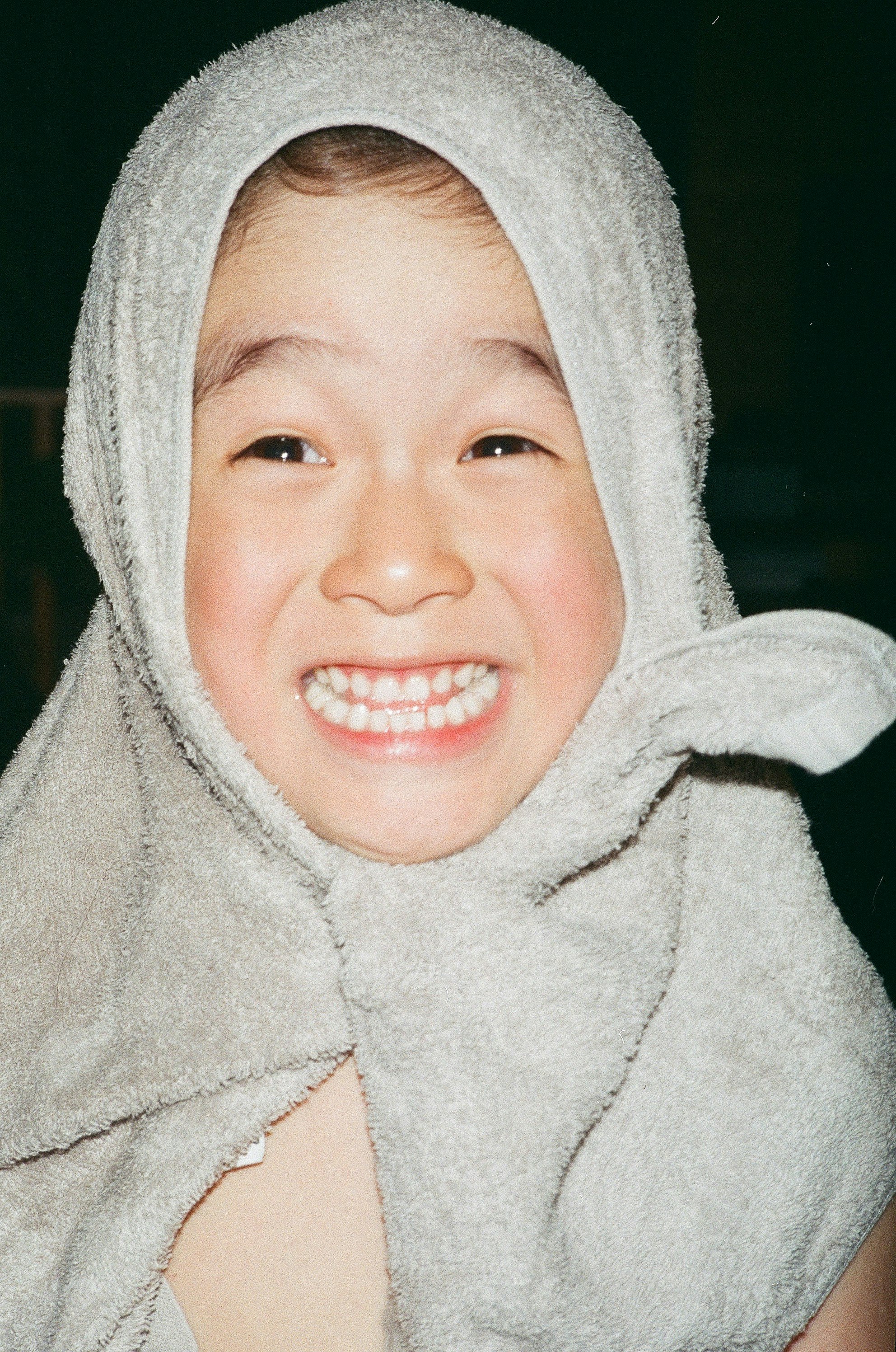 Close-up anak tersenyum memakai jaket abu-abu berhood gambar