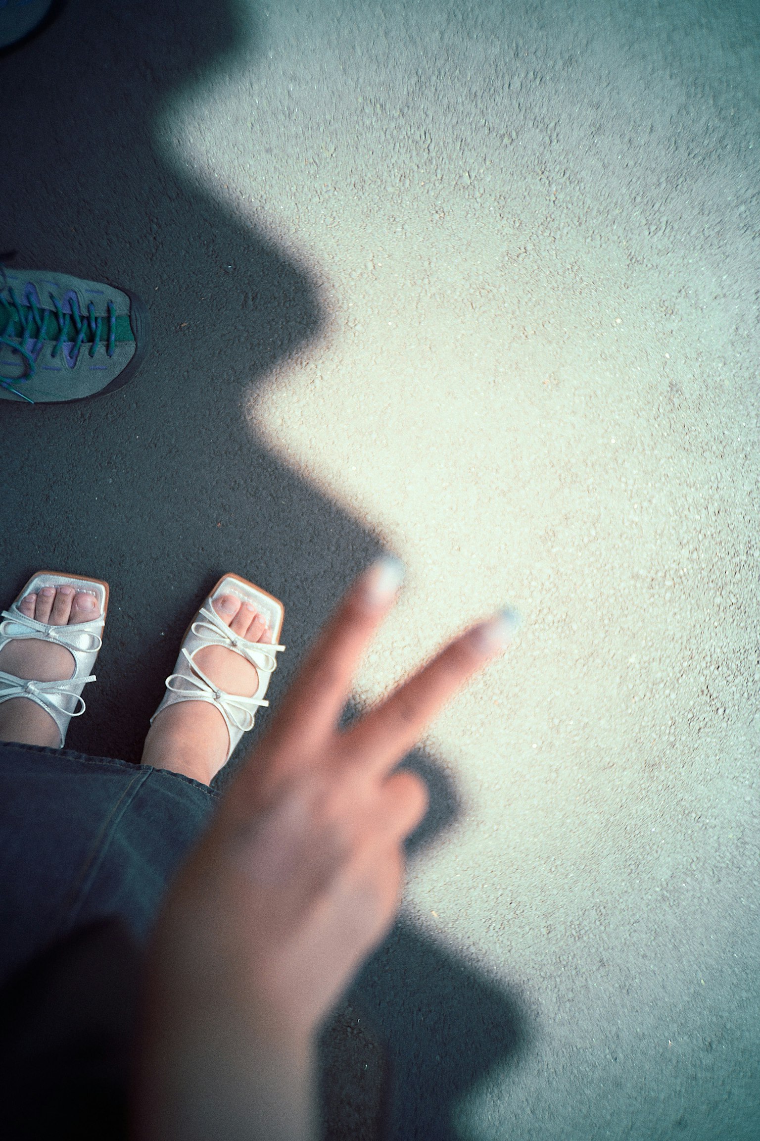 Piedi in sandali bianchi e una mano che fa un segno di pace proiettando un'ombra