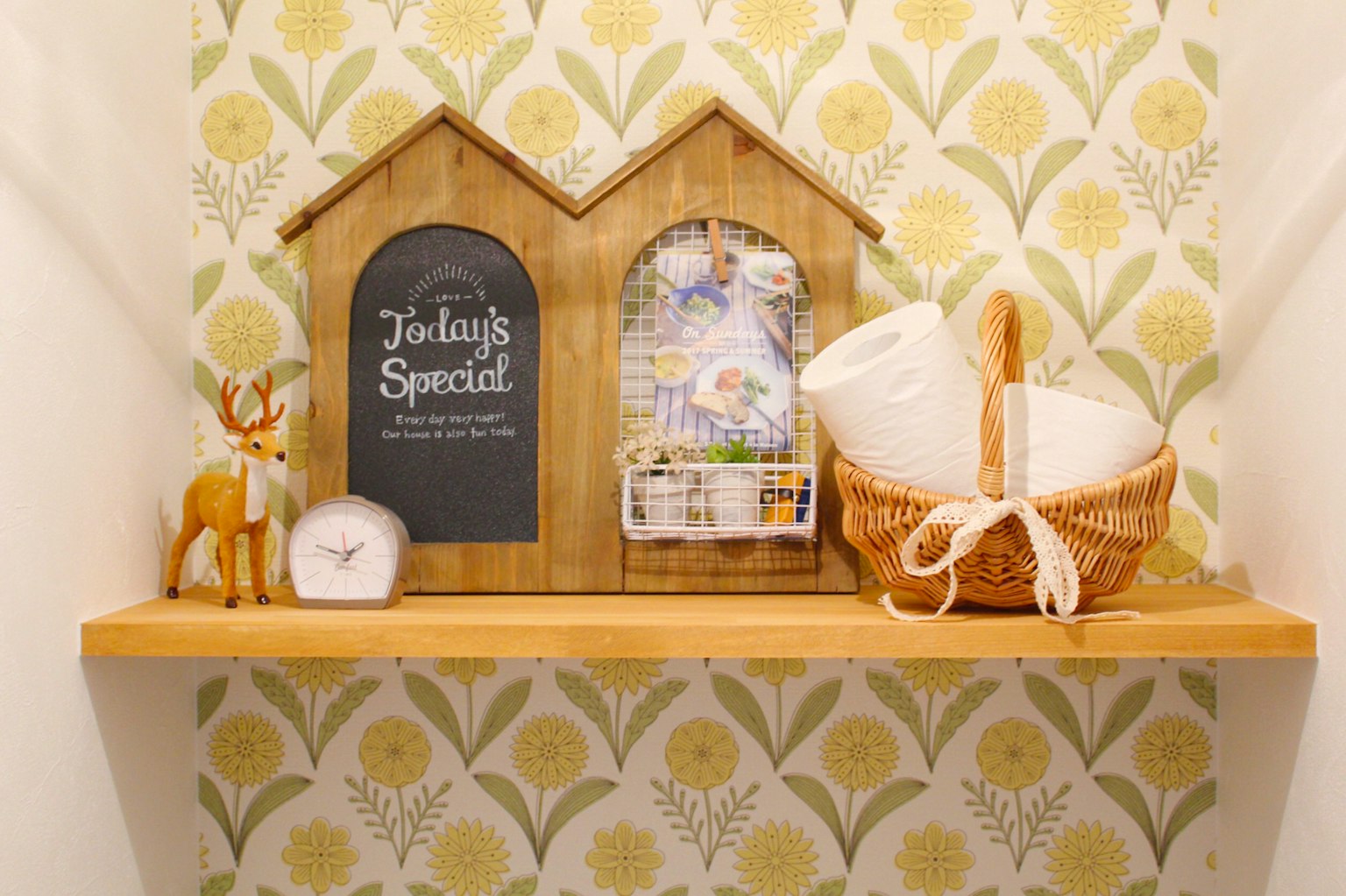 Estante en forma de casa de madera con objetos decorativos y papel tapiz floral