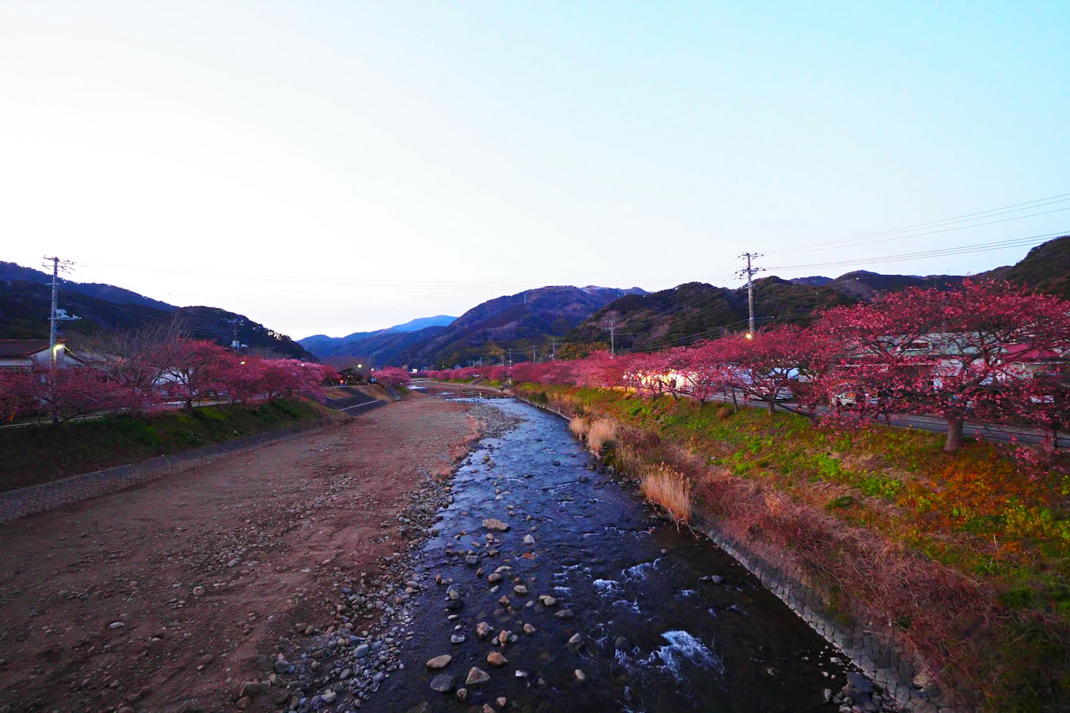 川と桜の木が並ぶ風景の写真山々と青い空が背景