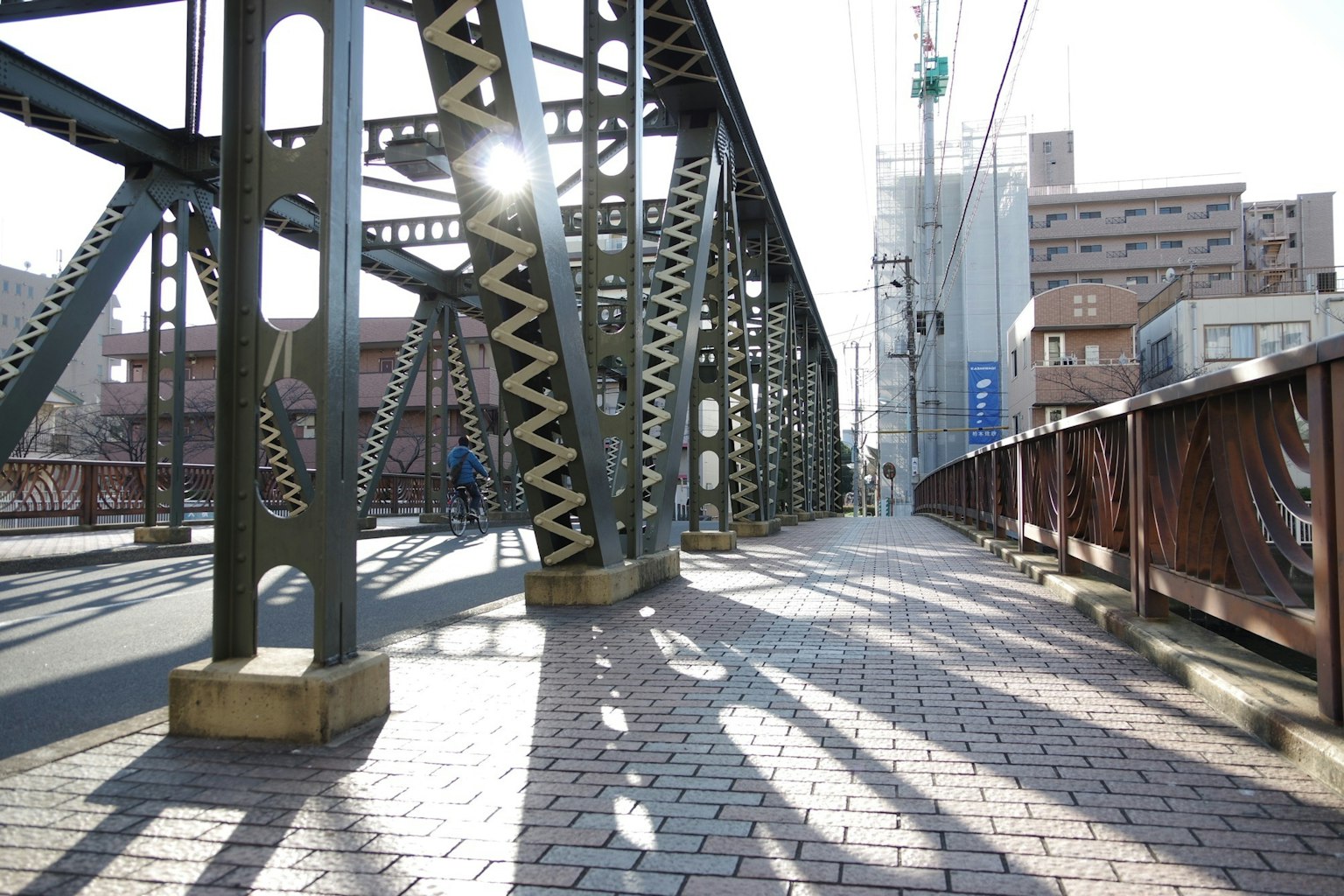 Marciapiede di un ponte in acciaio illuminato dal sole con ombre