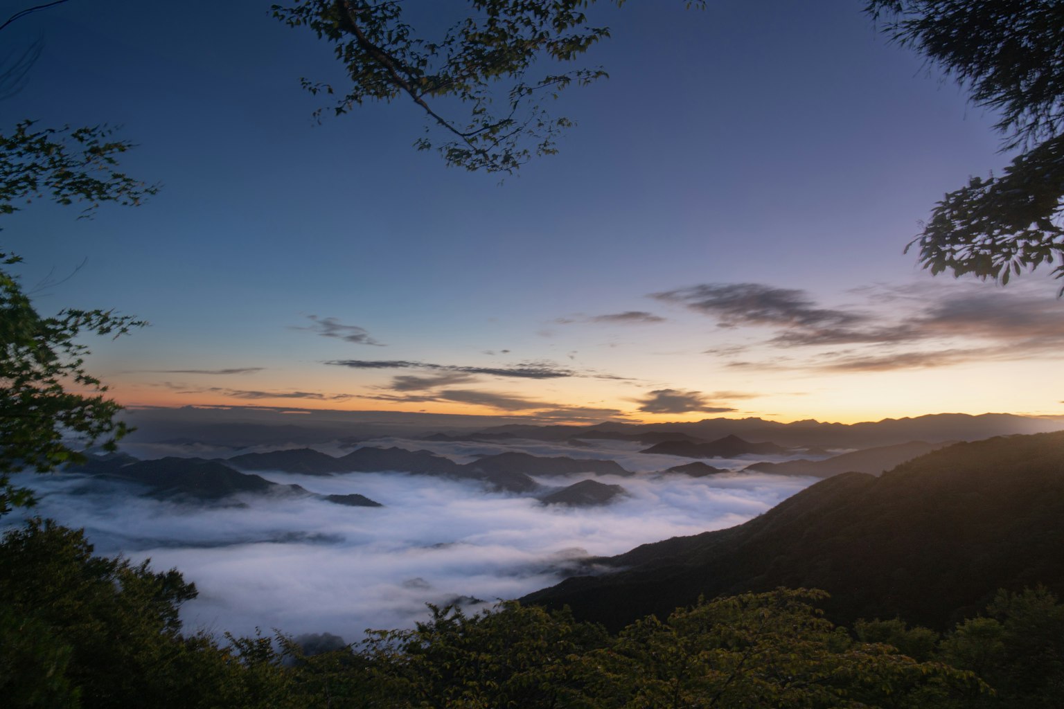 Scenic view of mist-covered mountains with colorful sunset sky
