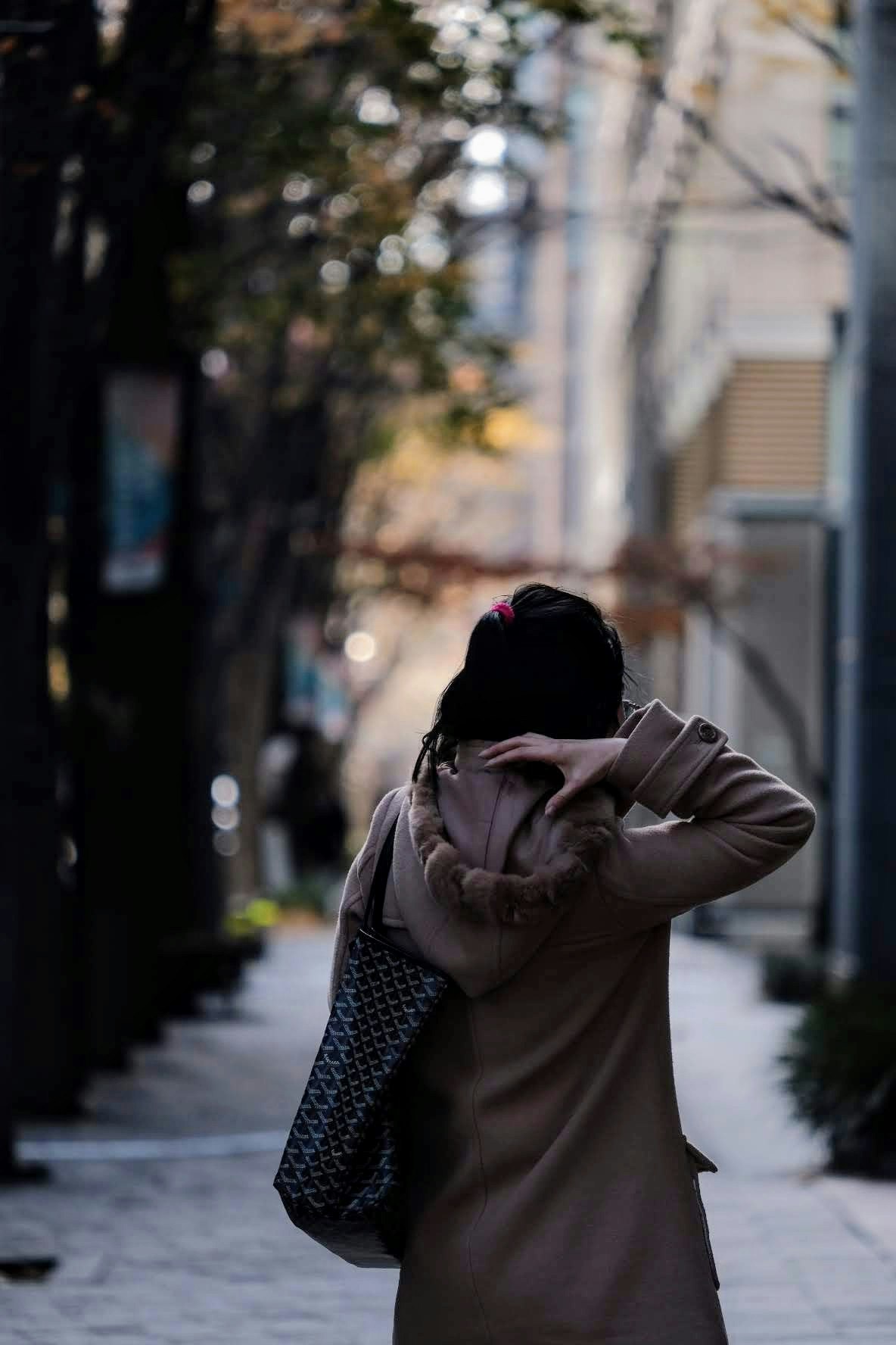 穿外套的人手提購物袋走在城市小巷裡