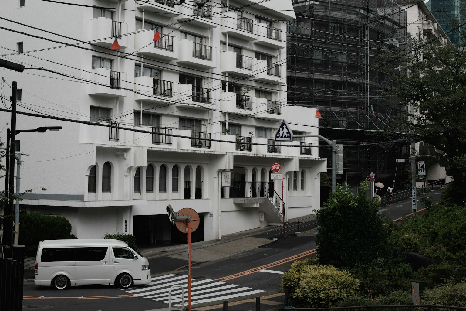 Weißes Gebäude mit Straßenansicht, Fahrzeug und Grünpflanzen