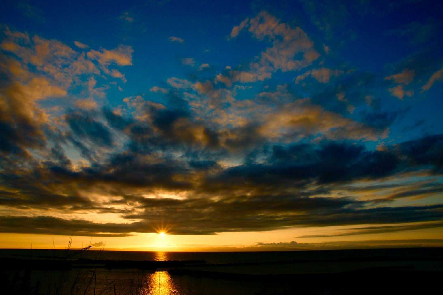 Bellissimo tramonto sull'oceano con cielo blu vibrante e nuvole arancioni