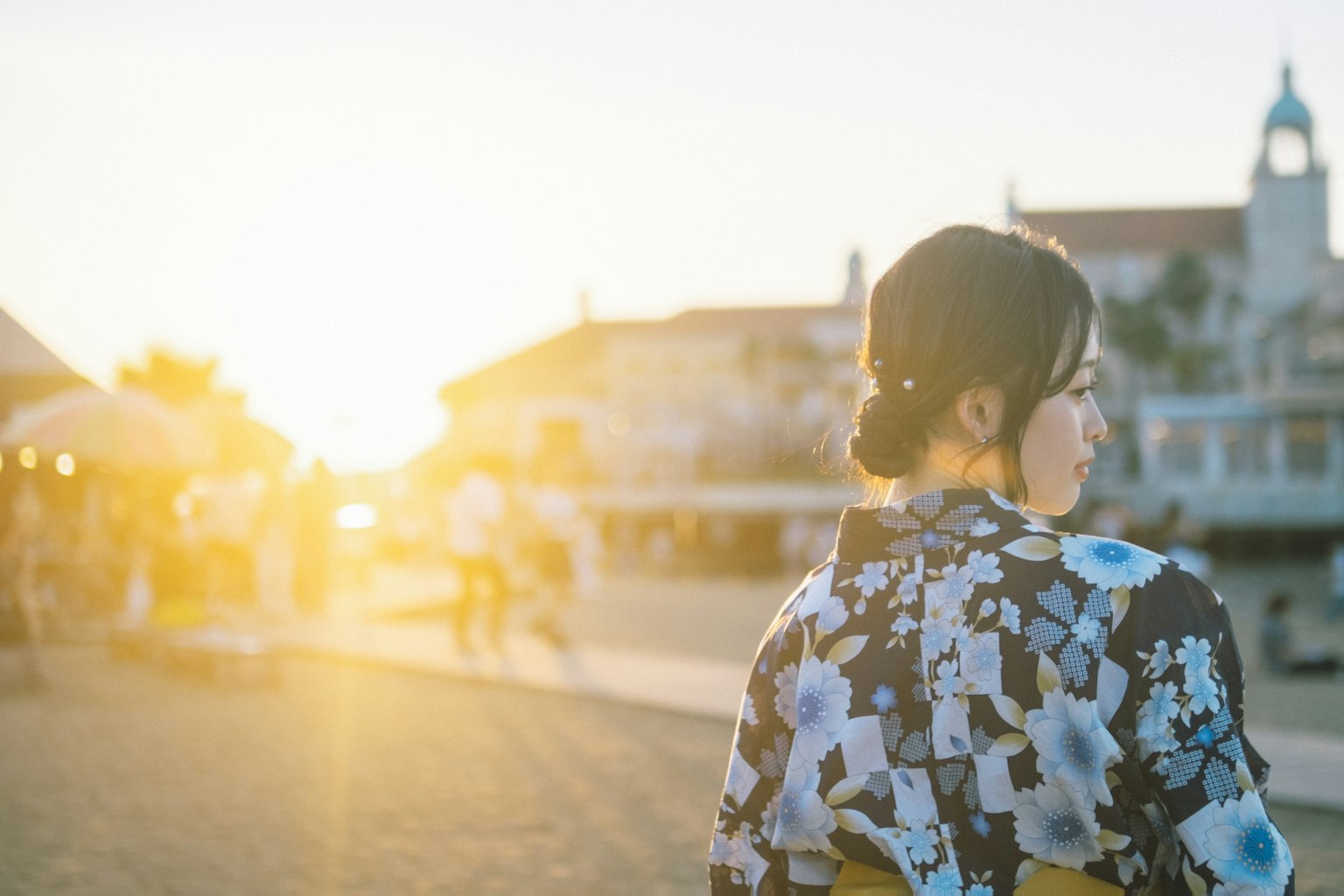 Một người phụ nữ trong trang phục kimono đứng với hoàng hôn phía sau