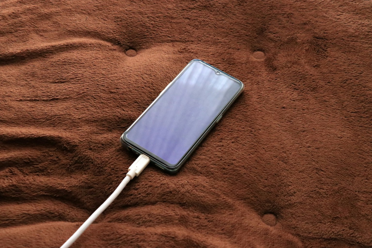 Smartphone lädt auf einer braunen Decke