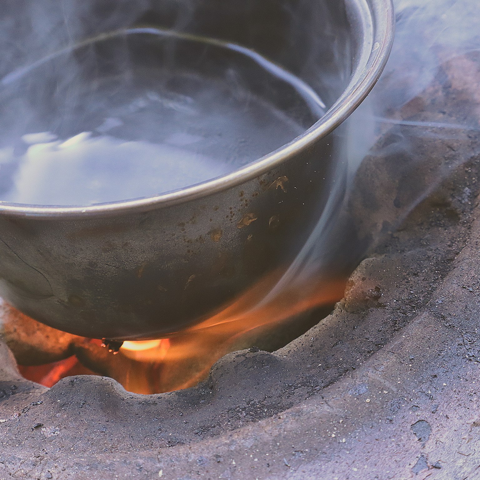 Une casserole chauffant de l'eau sur une flamme ouverte avec de la fumée s'élevant