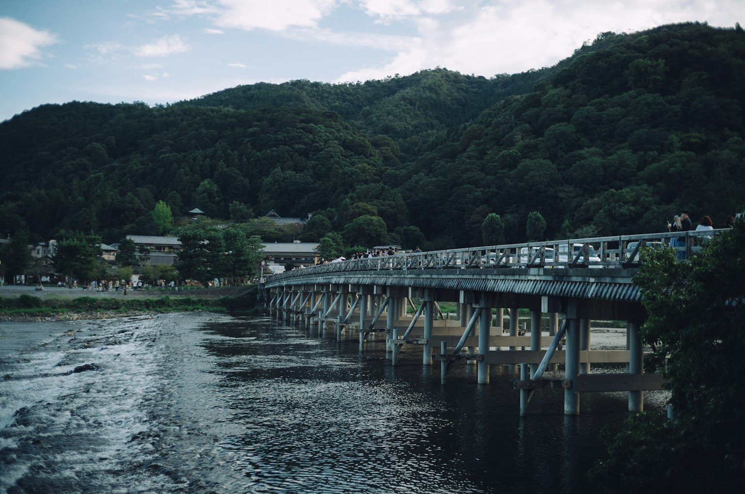 Brücke über einen ruhigen Fluss mit Bergen im Hintergrund