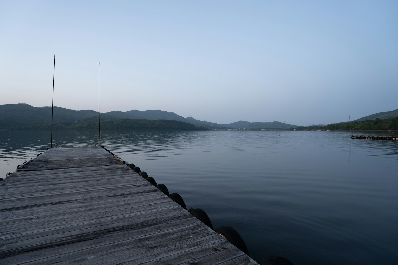 Vista serena del lago con un molo in legno sotto un cielo crepuscolare