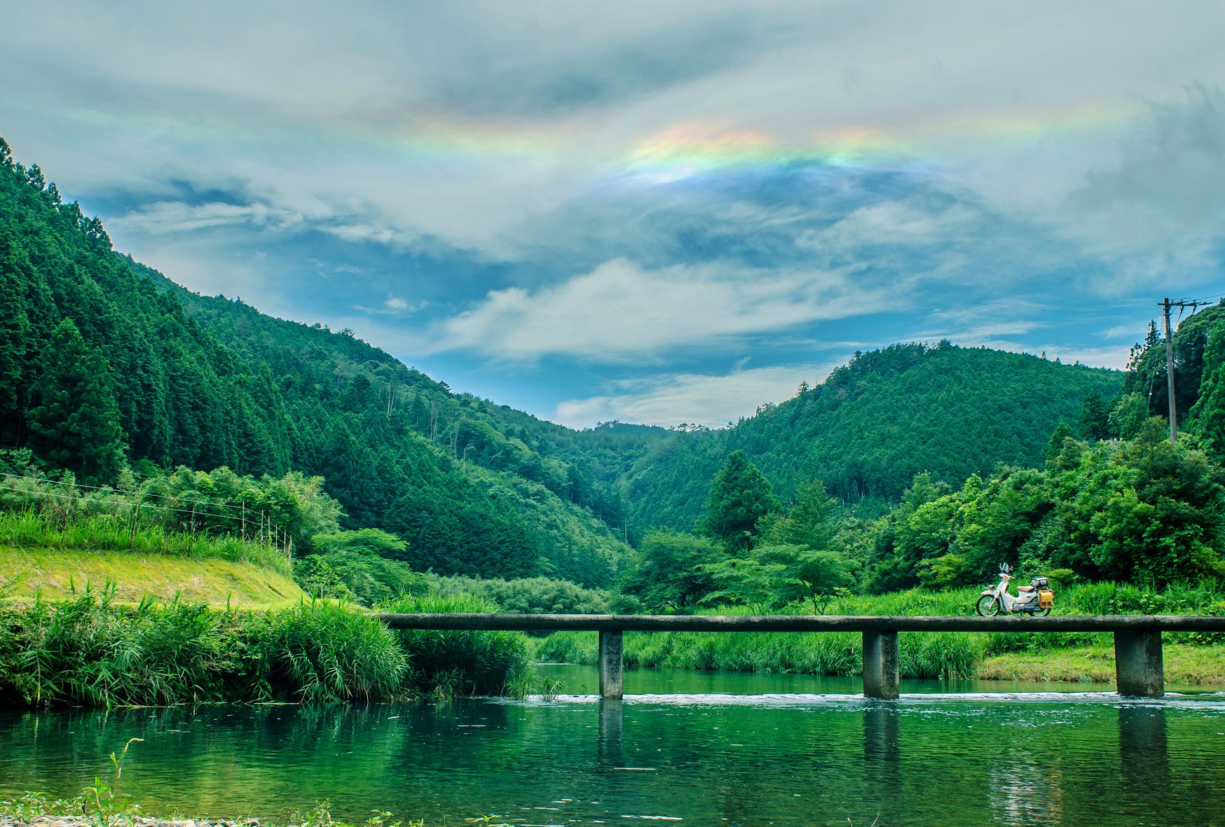 川と沈下橋、緑の山並みをバイクでツーリングする風景