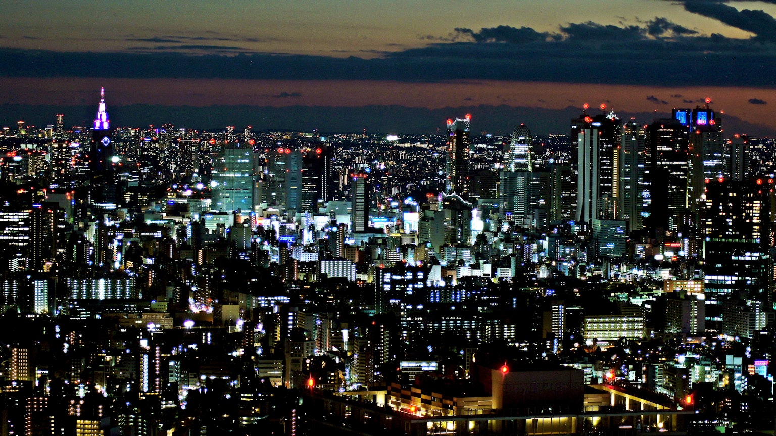 Pemandangan malam Tokyo dengan gedung pencakar langit dan lampu kota yang terang