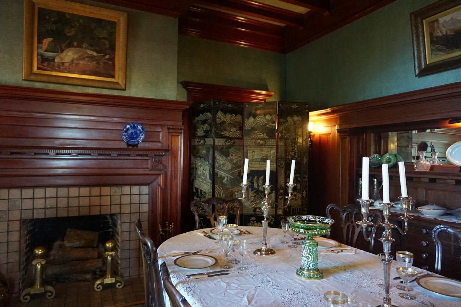 Interno di una sala da pranzo tradizionale con tavolo apparecchiato con candelabri e stoviglie quadri sulle pareti