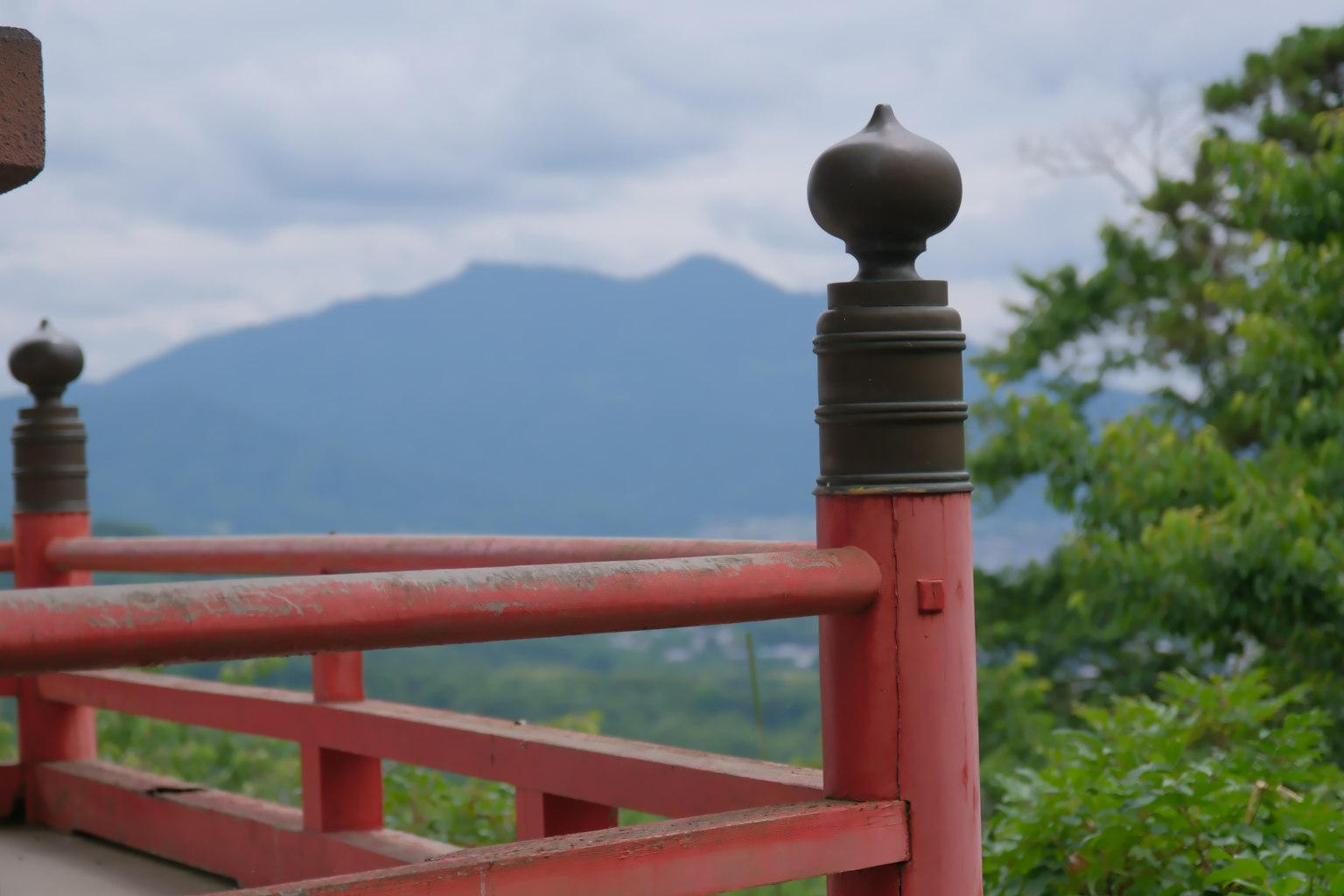 Red railing with metal ornament and mountains in the background