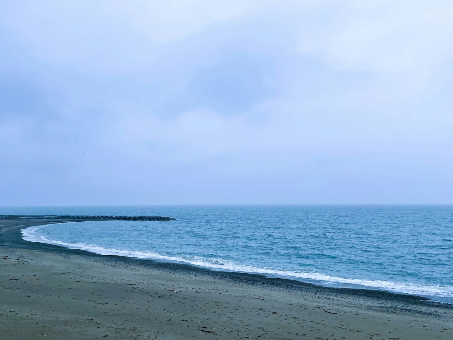 Paesaggio di spiaggia sereno sotto un cielo nuvoloso con onde gentili
