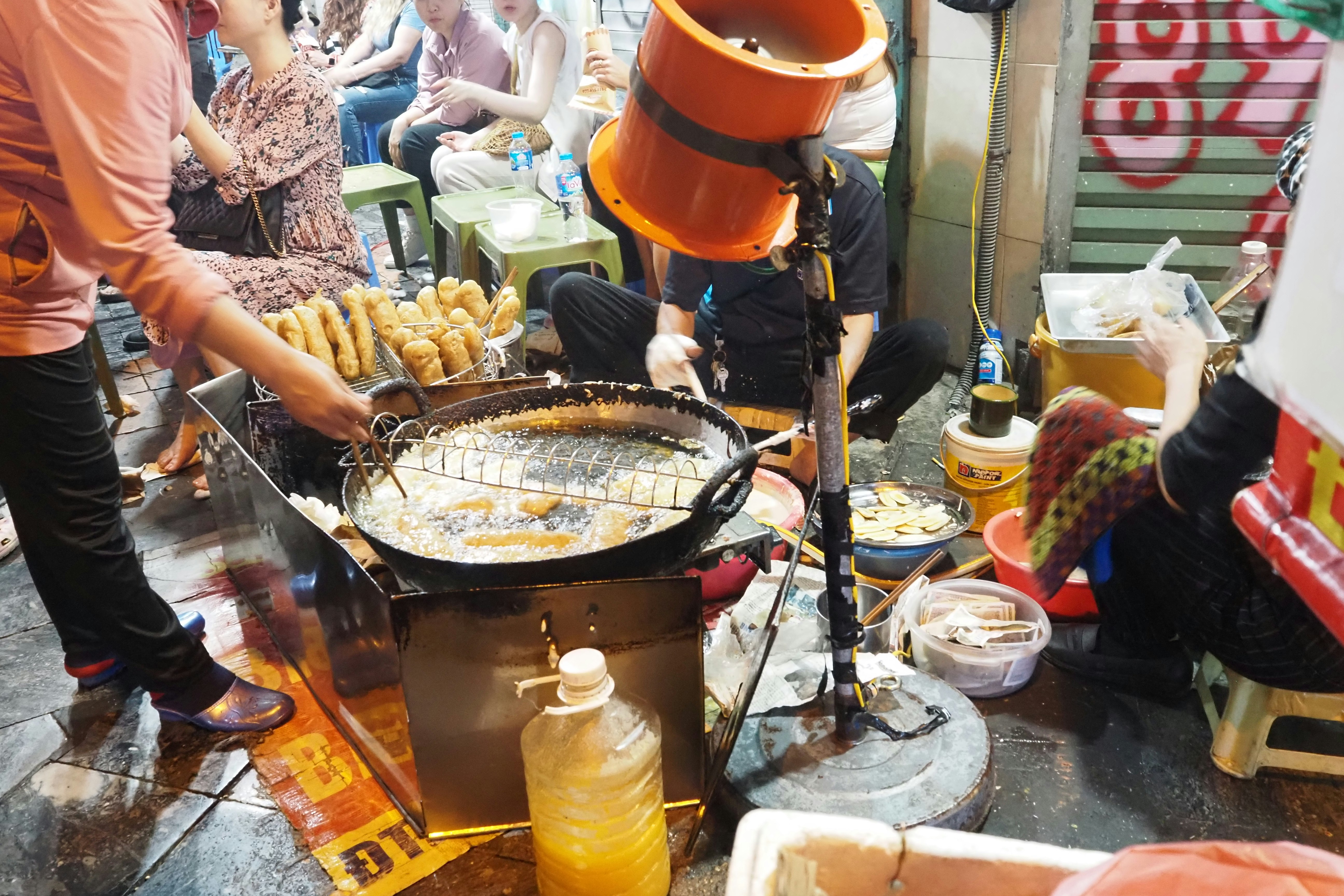 户外街头小吃摊，铁板上烤鱼与油炸小吃