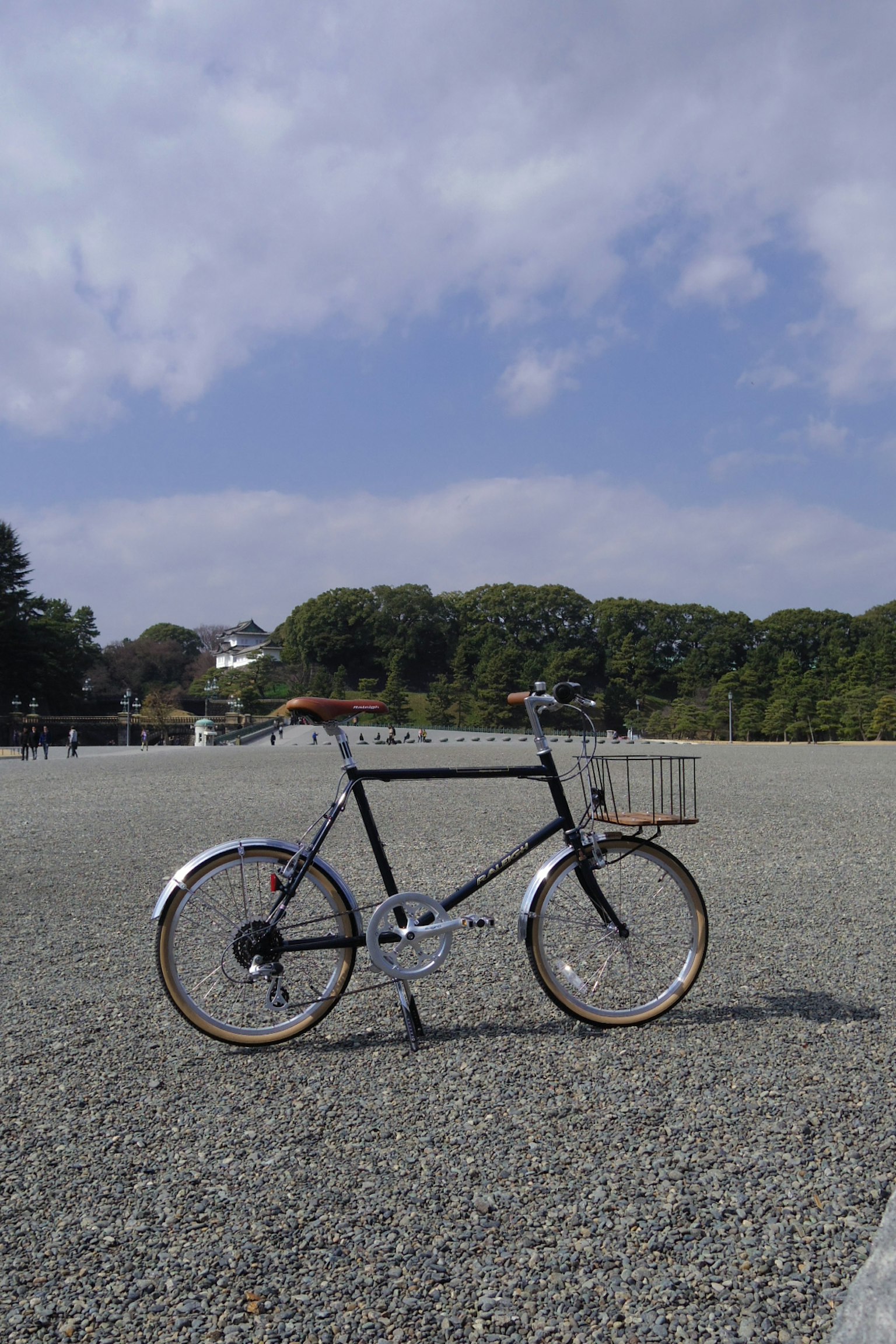 Un vélo noir se tenant sur un large champ de gravier sous un ciel bleu