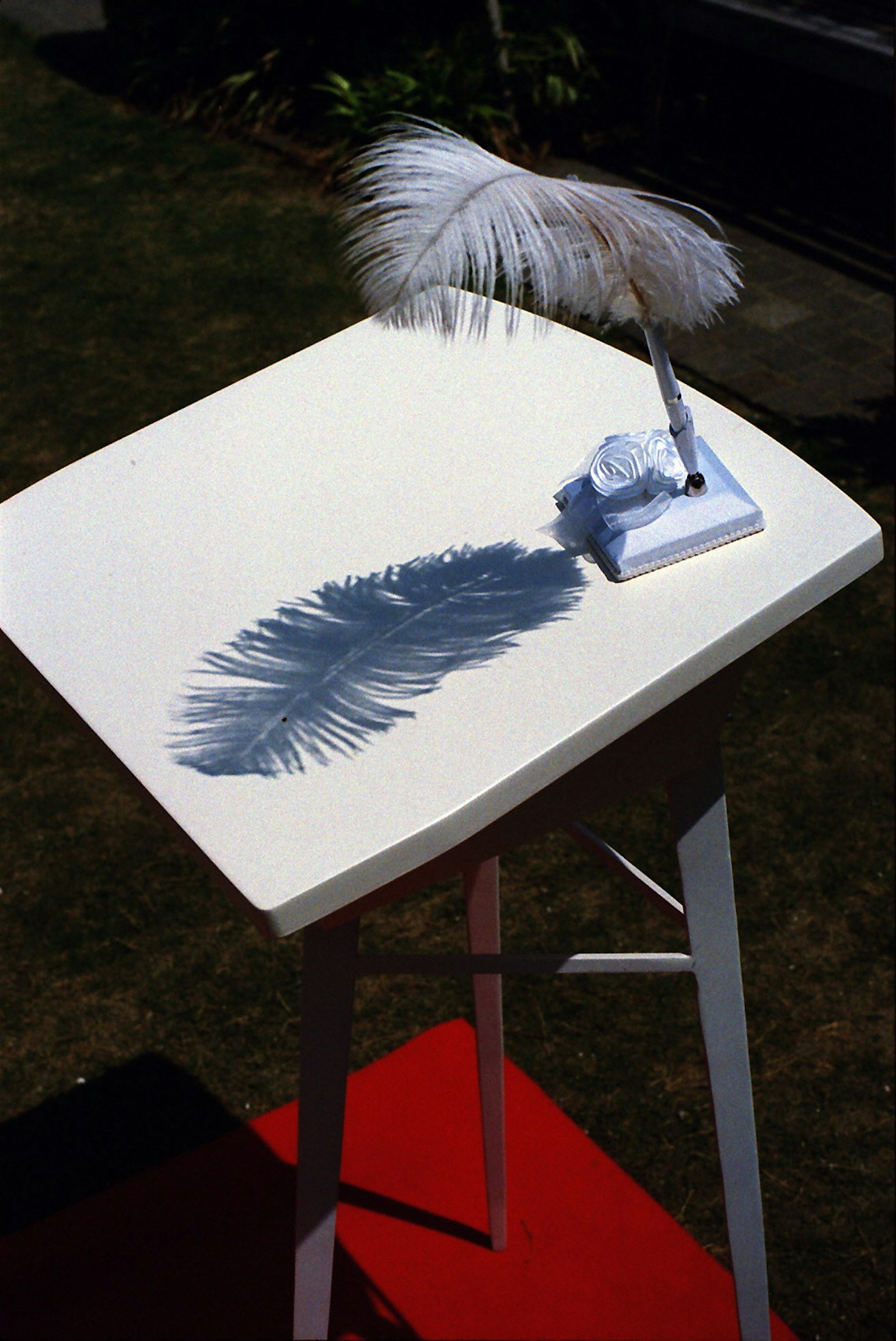Una mesa blanca con una pluma y su sombra