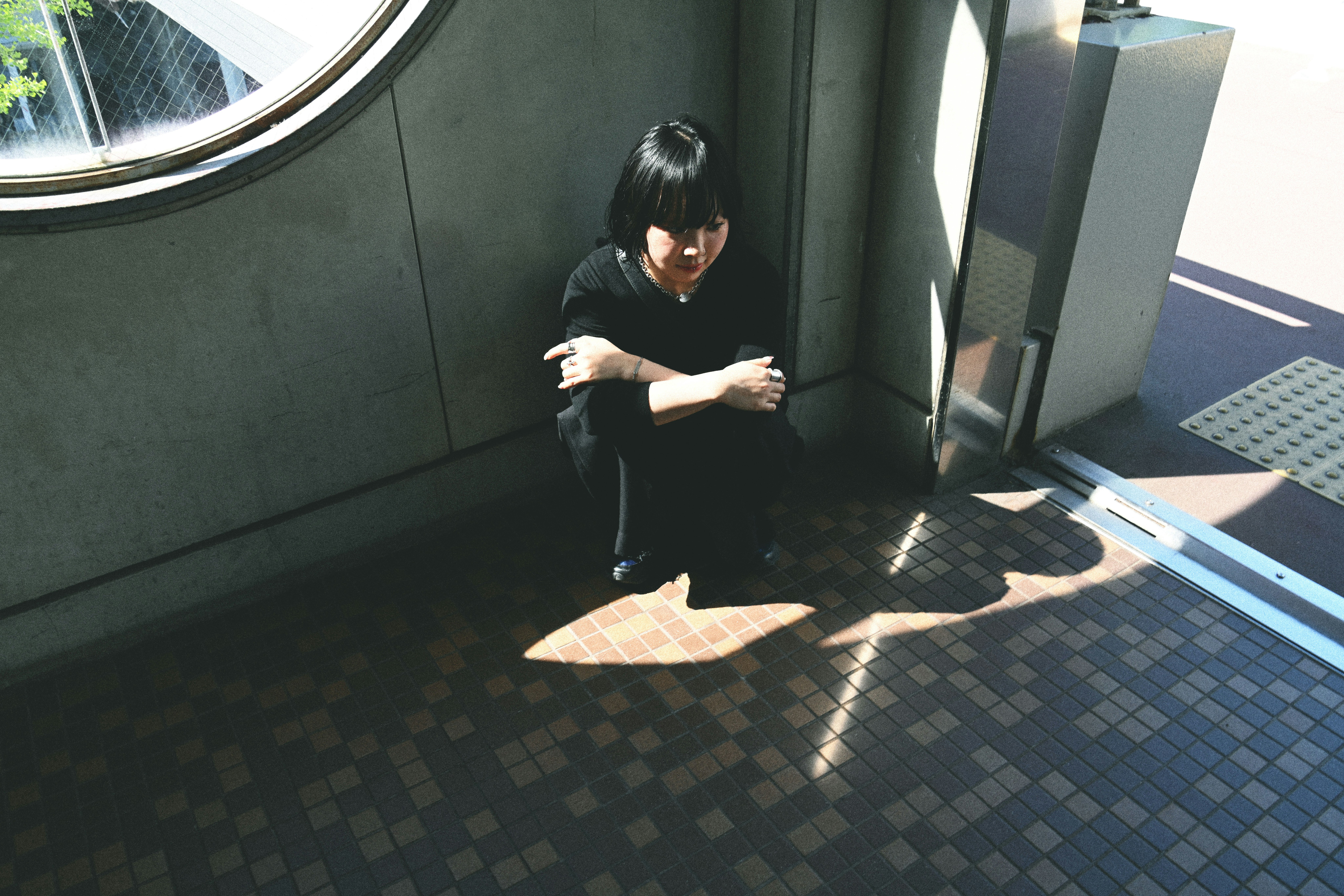 建物の壁際でスマホを見ている人物