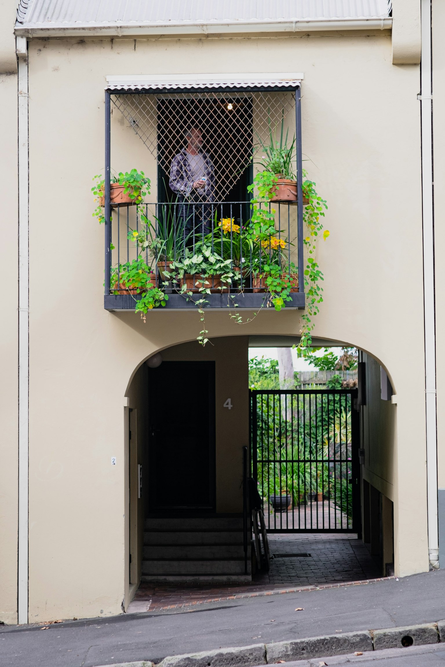 Esterno di un edificio con un balcone adornato di piante lussureggianti sopra un ingresso ad arco