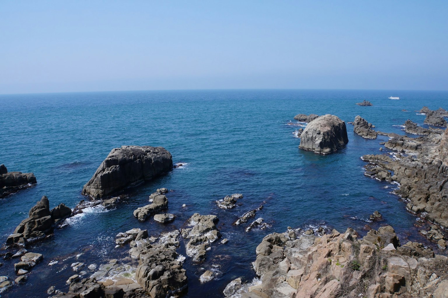 Pemandangan laut biru dan garis pantai berbatu dengan batu besar