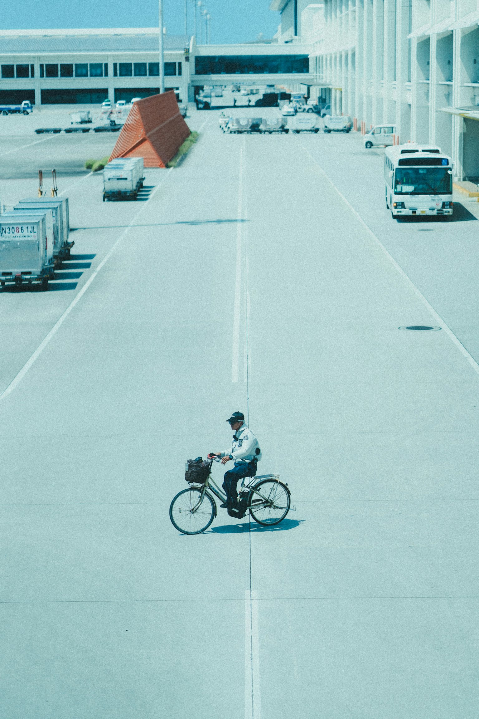 一个人在机场道路上骑自行车，背景有车辆