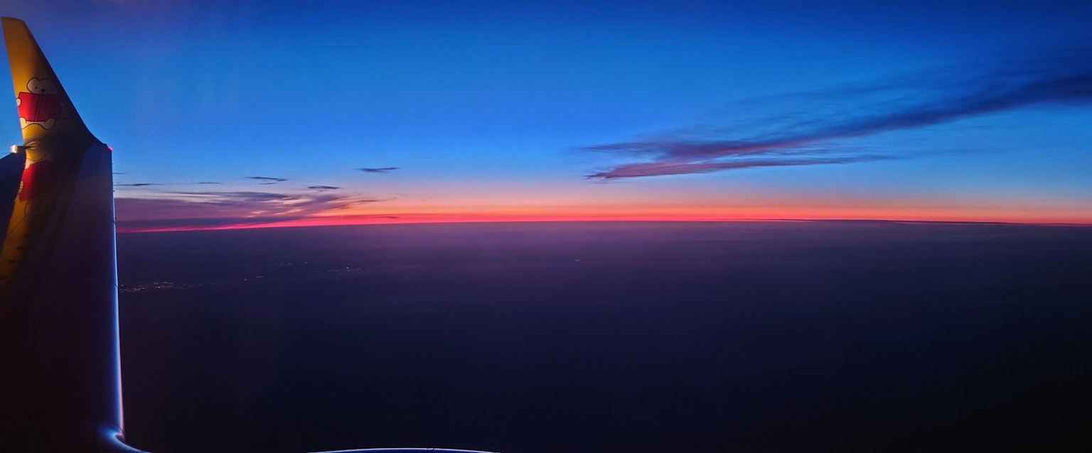 Sunset view from an airplane window featuring a gradient of blue and orange hues